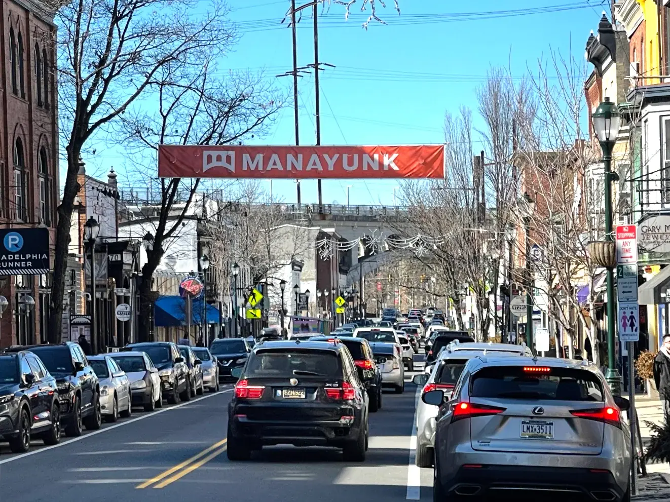 Main Street traffic beneath a Welcome to Manayunk banner